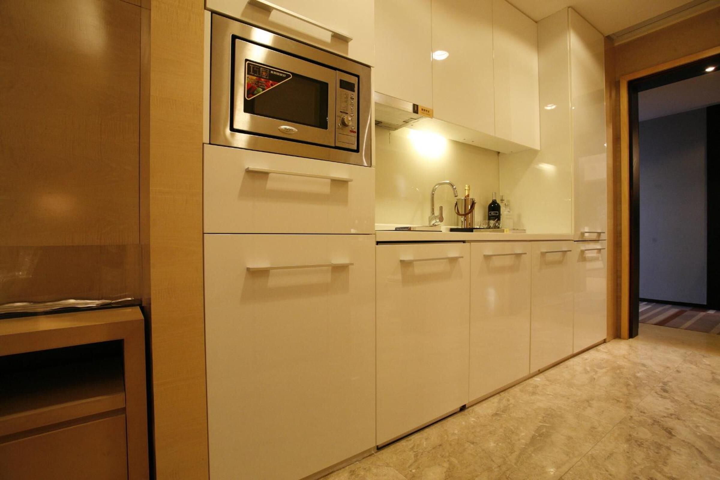 A modern kitchen with white cabinetry, a built-in microwave, and a stainless steel range hood.
