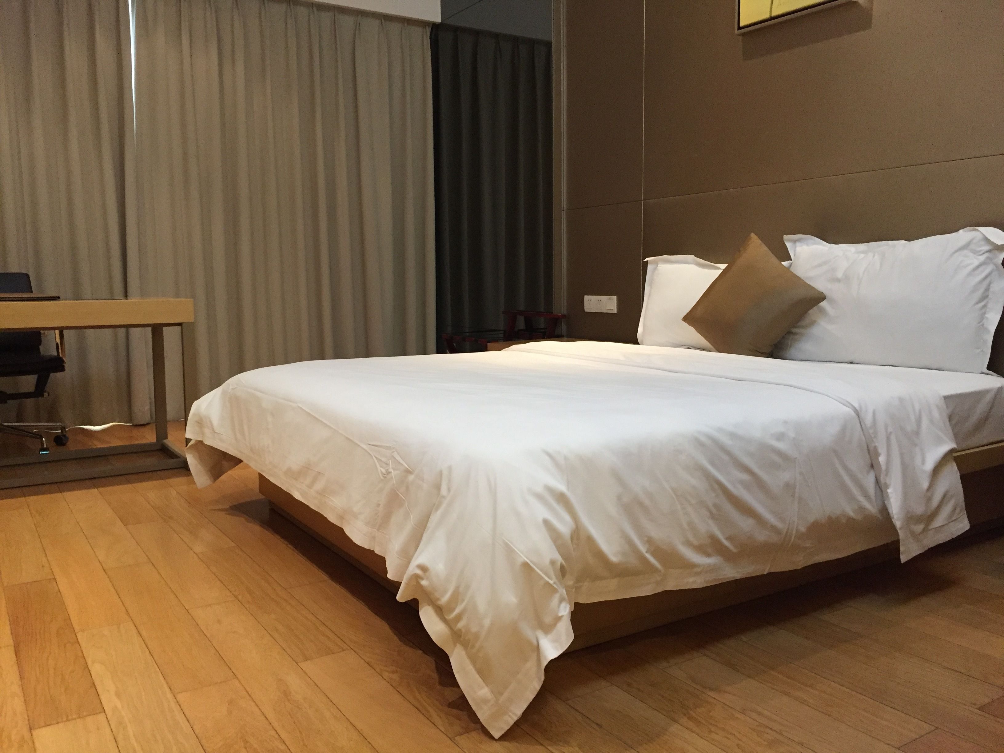 Hotellihuone, jossa on suuri sänky, työpöytä ja tuoli.