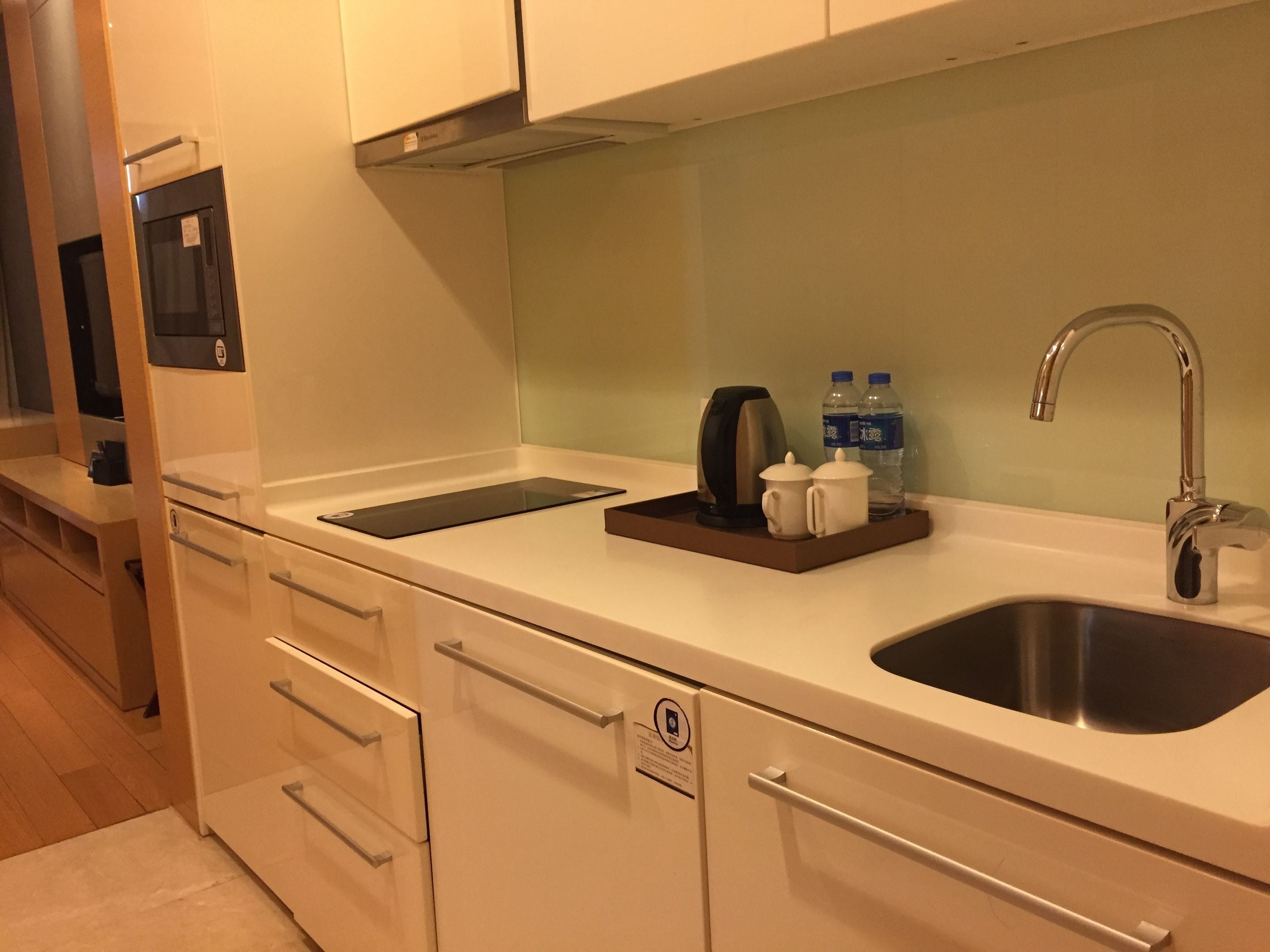 A modern kitchen with a stainless steel sink, a built-in coffee maker, and two water bottles on the countertop.