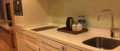 A modern kitchen with a stainless steel sink, a built-in coffee maker, and two water bottles on the countertop.