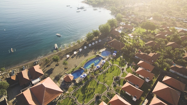 Relax by the pool or on the beach, surrounded by lush greenery and palm trees.