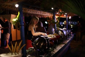 A food preparation area with cooking equipment and a person handling food. - Adi Assri Beach Resort & Spa (Pemuteran)