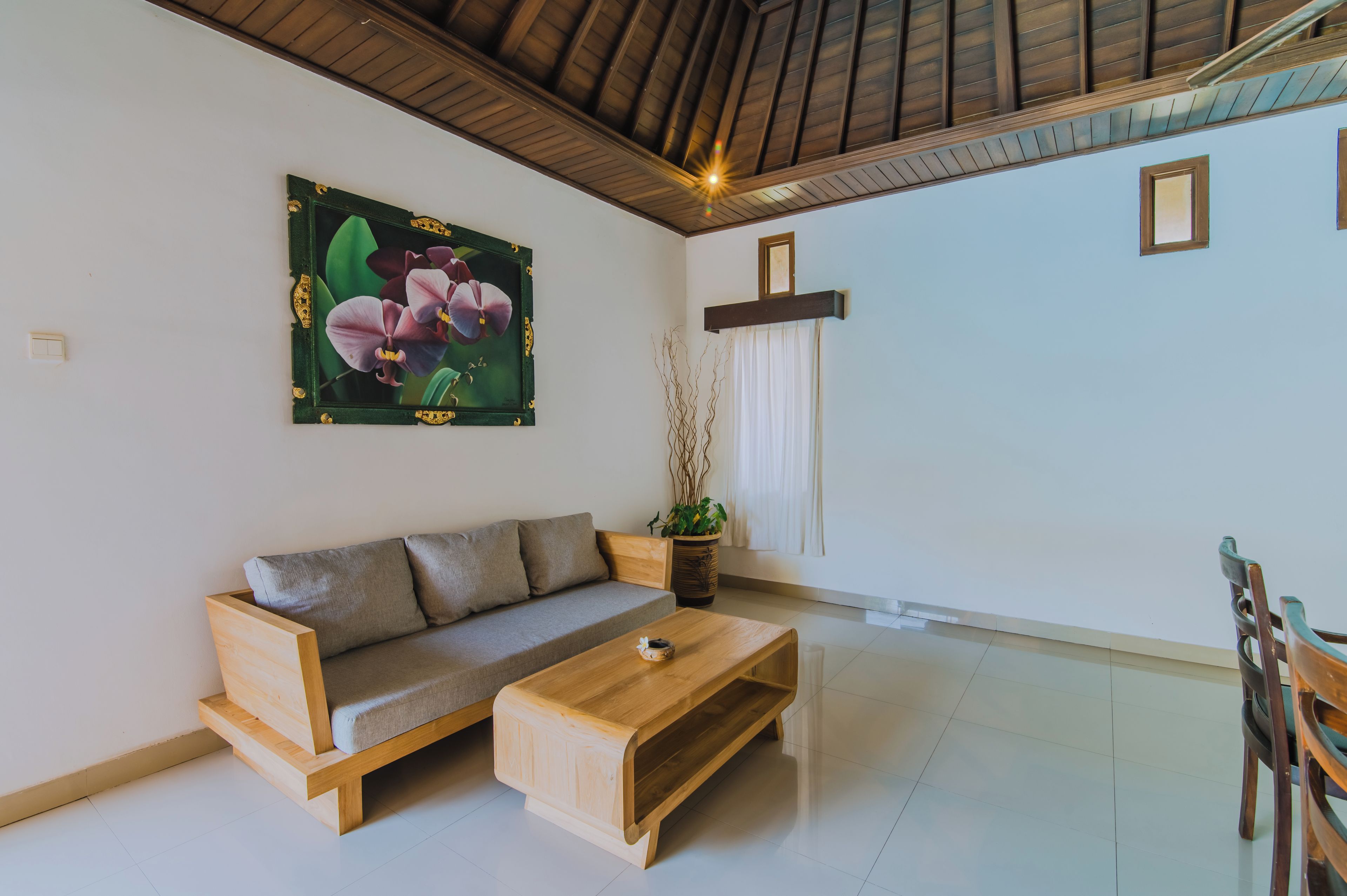 Una sala de estar con un sofá de madera, una mesa de centro y una planta en maceta.