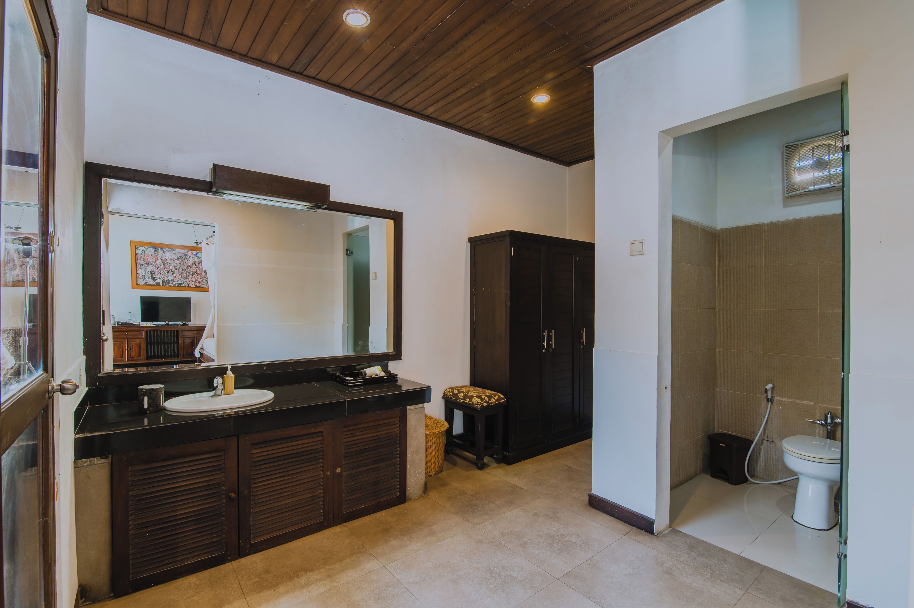 A bathroom with a wooden ceiling, a large mirror, a sink, a cabinet, and a shower area.