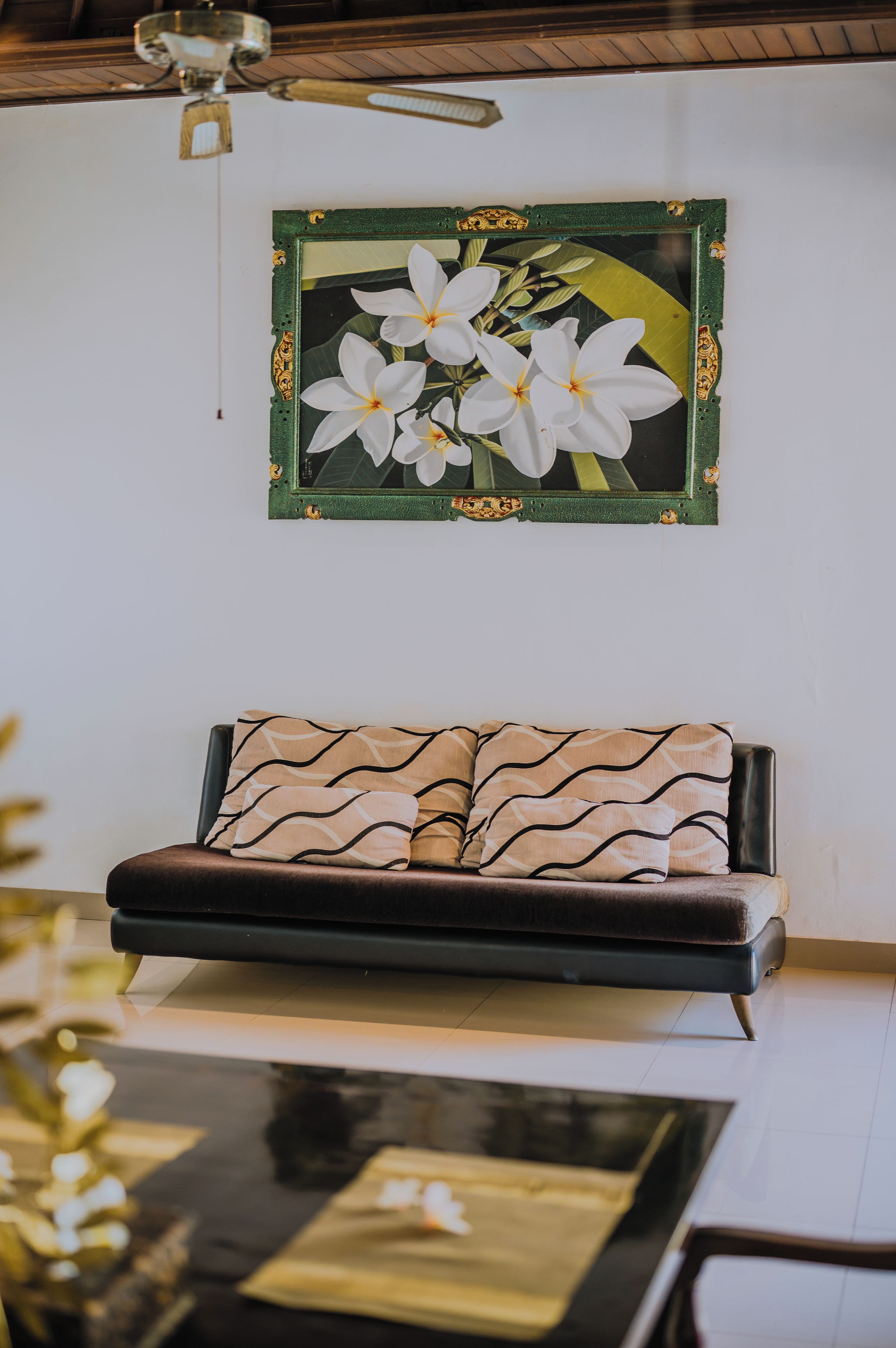 A room with a sofa, a framed picture on the wall, and a table with a vase.