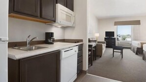 A compact hotel room with a kitchenette, a dining area, and a bed. - PetroStay Inn & Suites Cotulla (Cotulla)