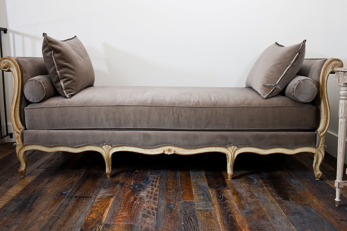 Un sofá de diseño clásico sobre un piso de madera.