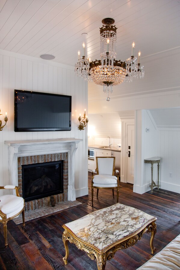 A living room with a fireplace, a television mounted above it, and a chandelier.