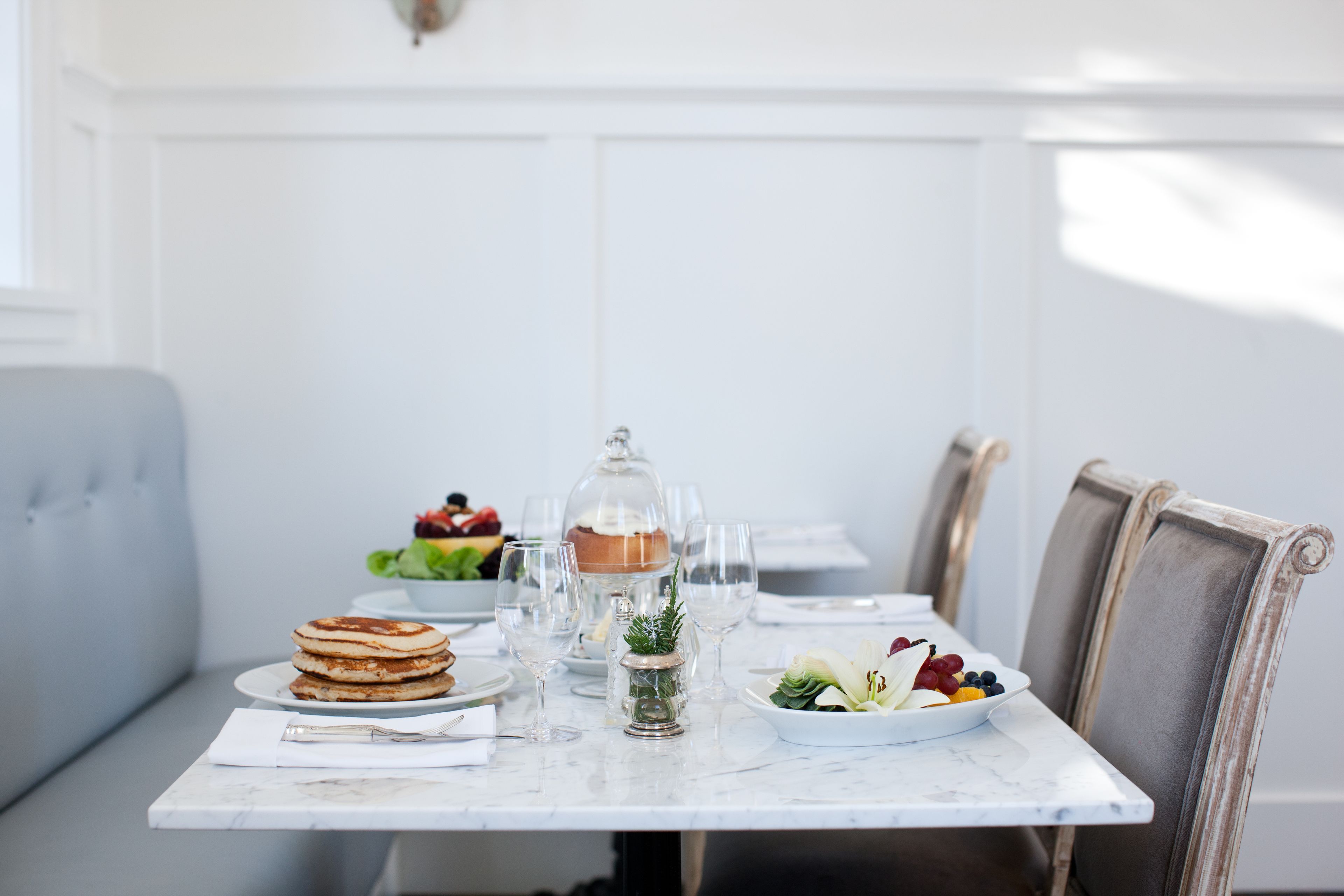 A dining table with a white marble top, surrounded by chairs with wooden frames.