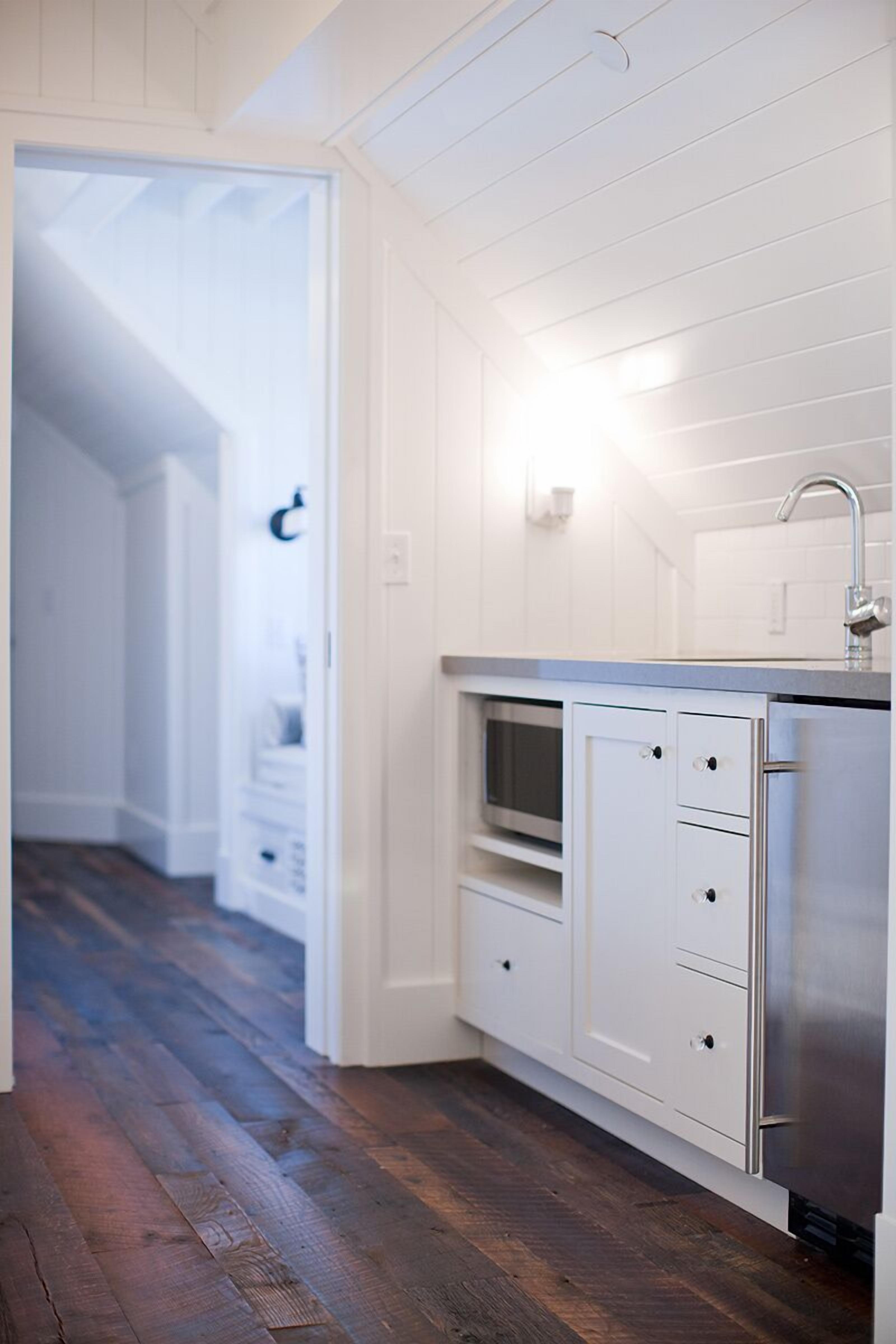A modern kitchen with white cabinetry, a stainless steel refrigerator, and a built-in microwave.