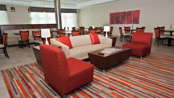 A hotel lobby with a sofa, armchairs, a coffee table, and a patterned carpet.