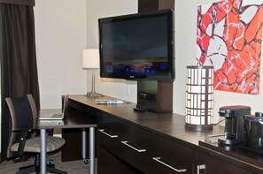 A hotel room with a flat-screen TV, a desk with a laptop, a coffee maker, and a decorative lamp. - Holiday Inn Express & Suites Columbus - Easton Area by IHG (Columbus)