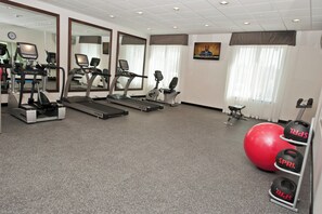 Un gimnasio con cintas de correr, bicicletas estáticas y pelotas de ejercicio.