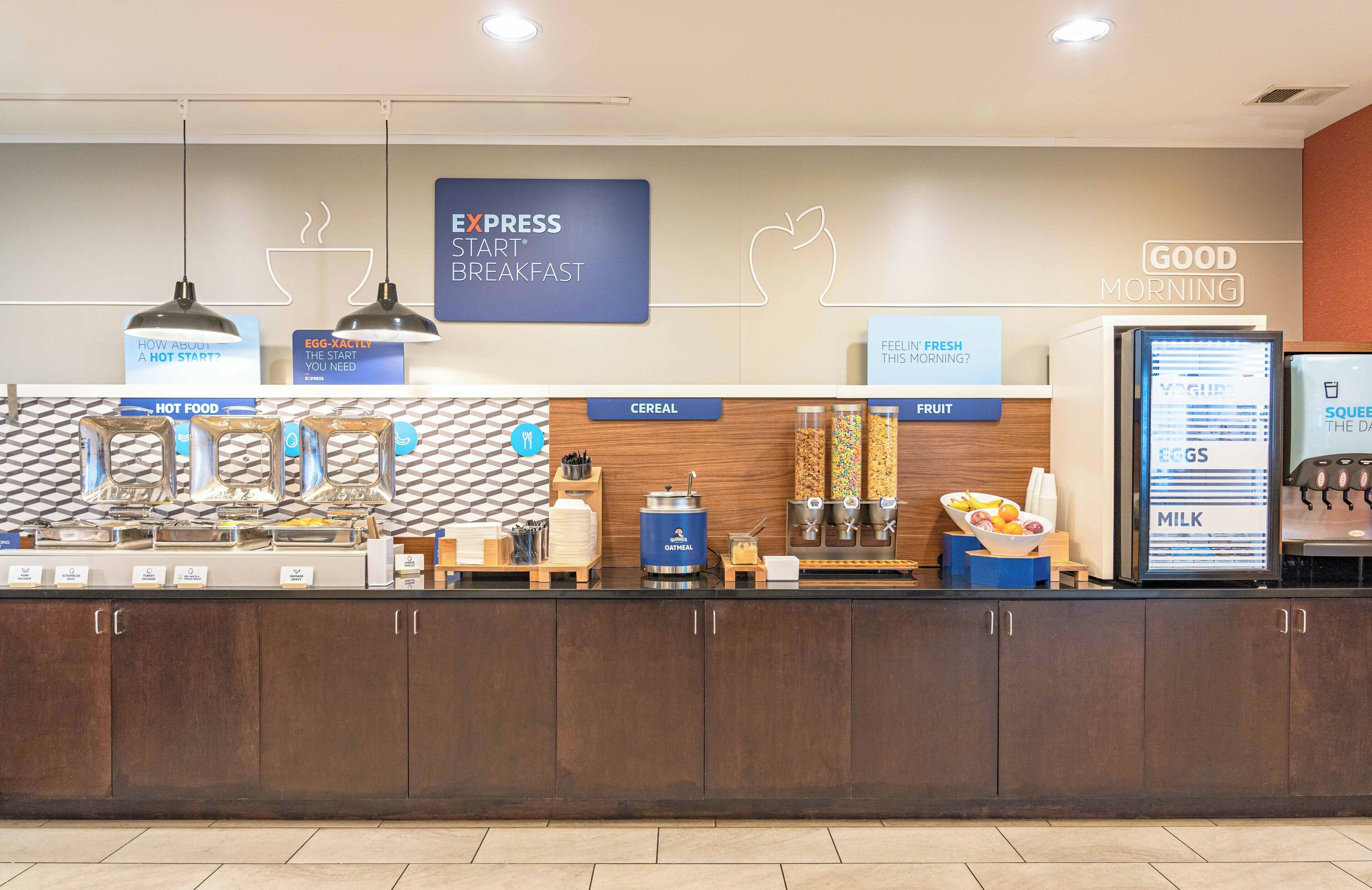 A breakfast bar with labeled food stations including cereal, fruit, and yogurt.