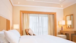 Une chambre d’hôtel avec un grand lit, un bureau en bois, une chaise et un miroir.