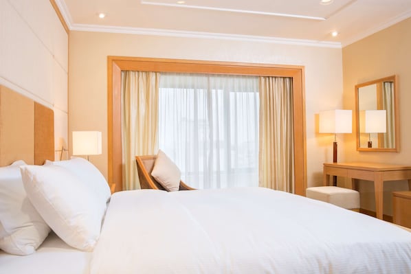 A hotel room with a large bed, a wooden desk, a chair, and a mirror. - Hilton Garden Inn Hanoi (Hanoi)