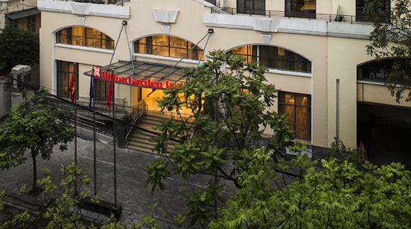 A hotel with a prominent red sign, a covered entrance, and a staircase leading to the entrance.
