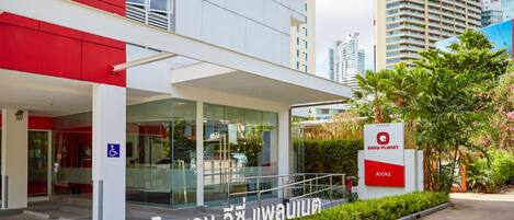 A modern building with a red and white facade, a glass entrance, and a sign indicating 'Easy Planet Asoke'.