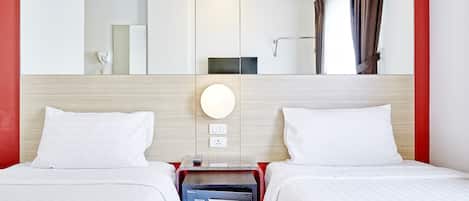 Habitación de hotel con dos camas, un espejo grande, ventilador de techo, equipo de aire acondicionado y una pared de acento roja.