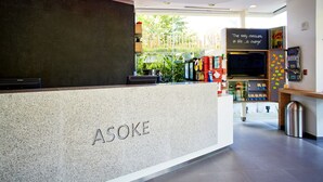 A reception area with a modern design, featuring a reception desk labeled "ASOKE" and a quote on the wall. - Easy Planet Bangkok Asoke (Bangkok)