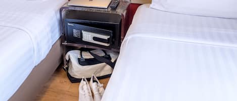 Habitación de hotel con dos camas, una laptop sobre la mesita de noche, un televisor portátil y una bolsa en el suelo.