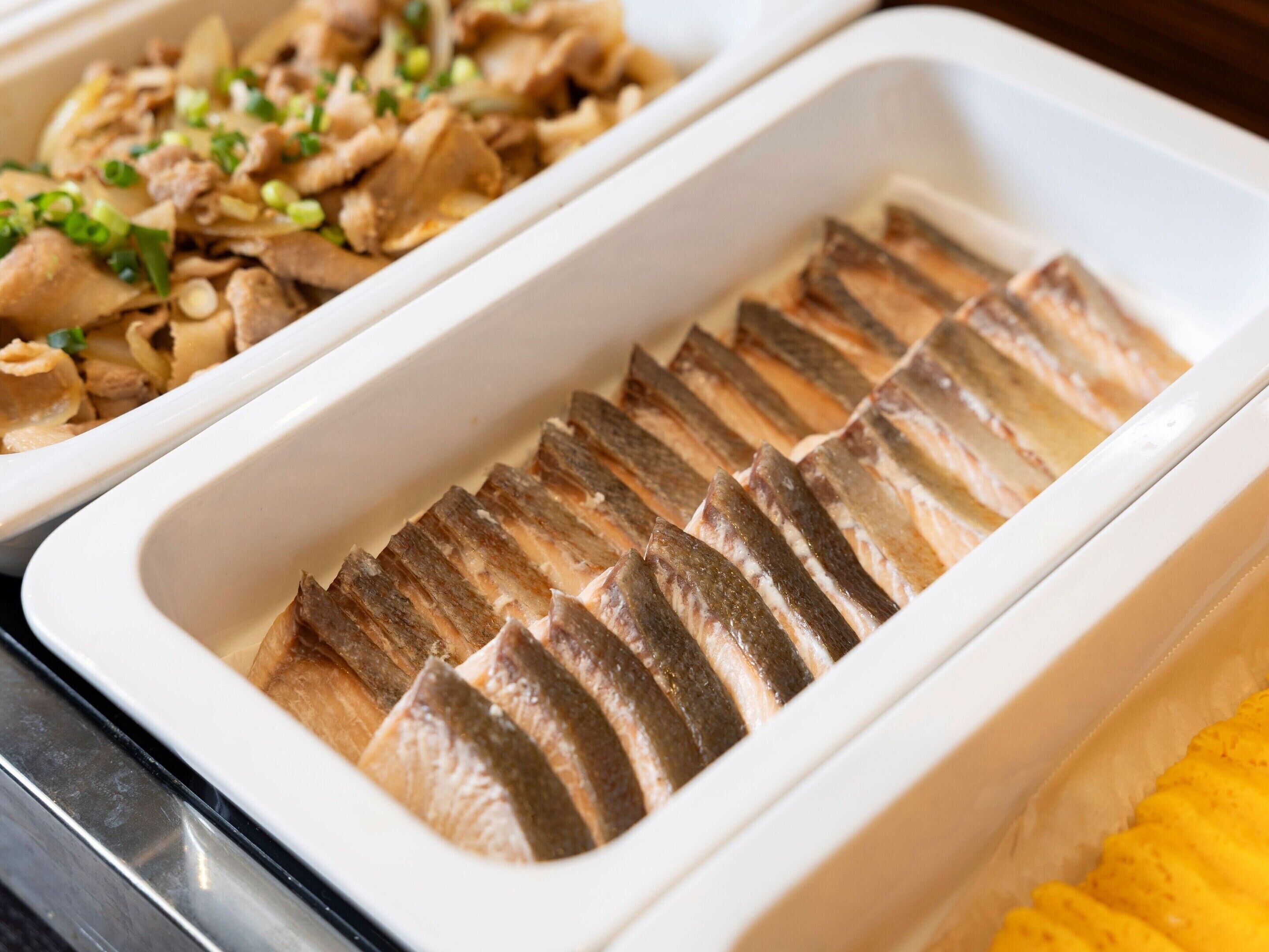 Ein Buffet mit Fischscheiben und einem Gericht mit Fleisch und Gemüse.
