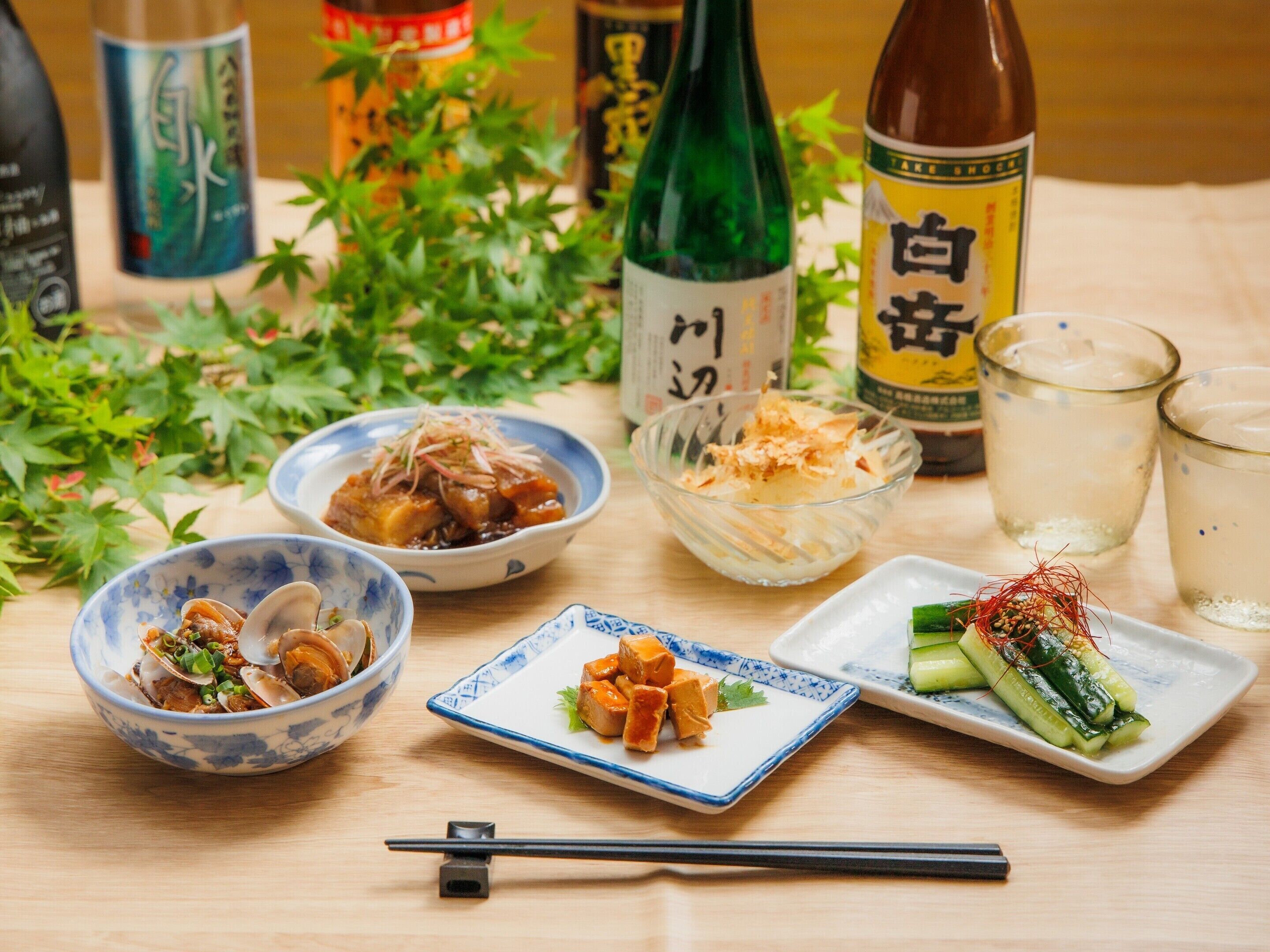 A table with various dishes, including seafood, tofu, and vegetables, accompanied by drinks and chopsticks.