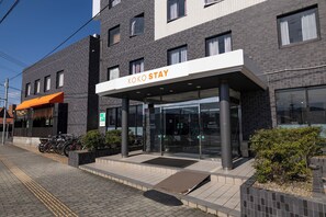 A modern building with a sign reading 'KOKO STAY' and a covered entrance. - KOKO STAY Kumamoto Yatsushiro (Yatsushiro)