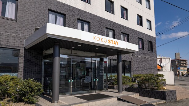 A modern building with a sign reading 'KOKO STAY' and a glass entrance. - KOKO STAY Kumamoto Yatsushiro (Yatsushiro)