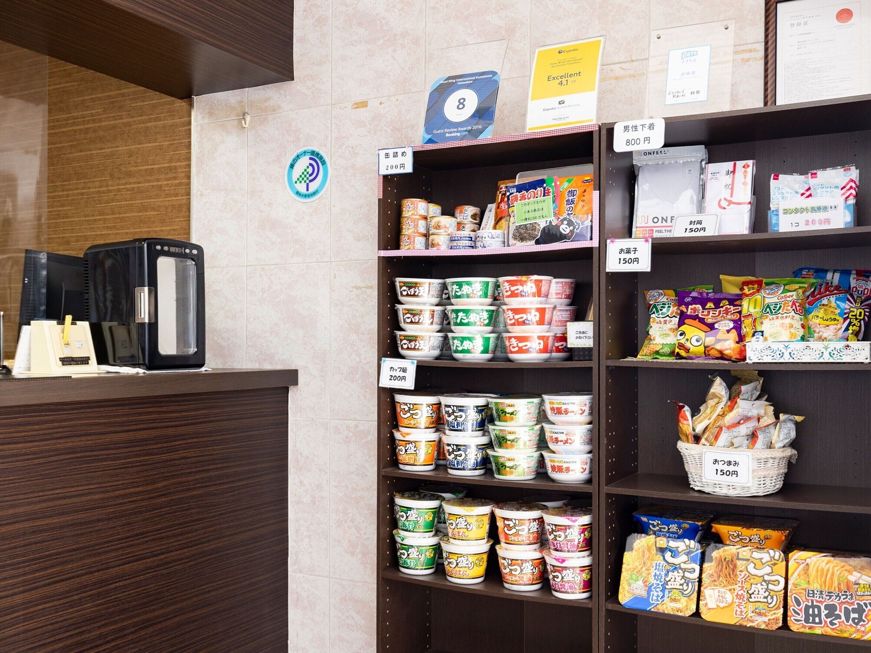 Un sector de autoservicio con diversos alimentos y bebidas envasados, como fideos instantáneos y aperitivos, con etiquetas de precio visibles.