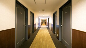 A hotel hallway with doors numbered 2109 and 2112, carpeted floor, and a ceiling light fixture. - KOKO STAY Kumamoto Yatsushiro (Yatsushiro)