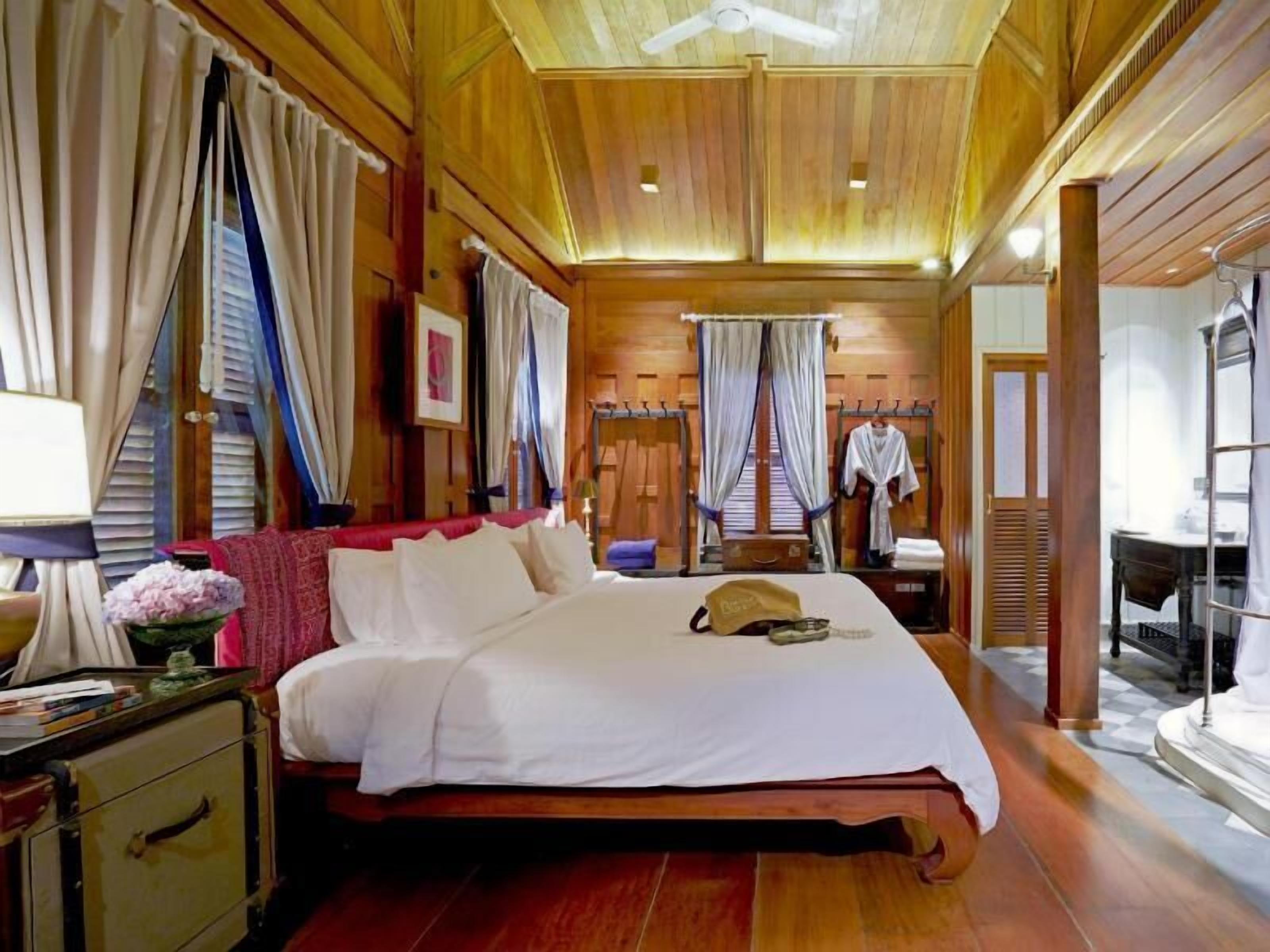 A wooden-paneled room with a bed, a desk, and a chair.