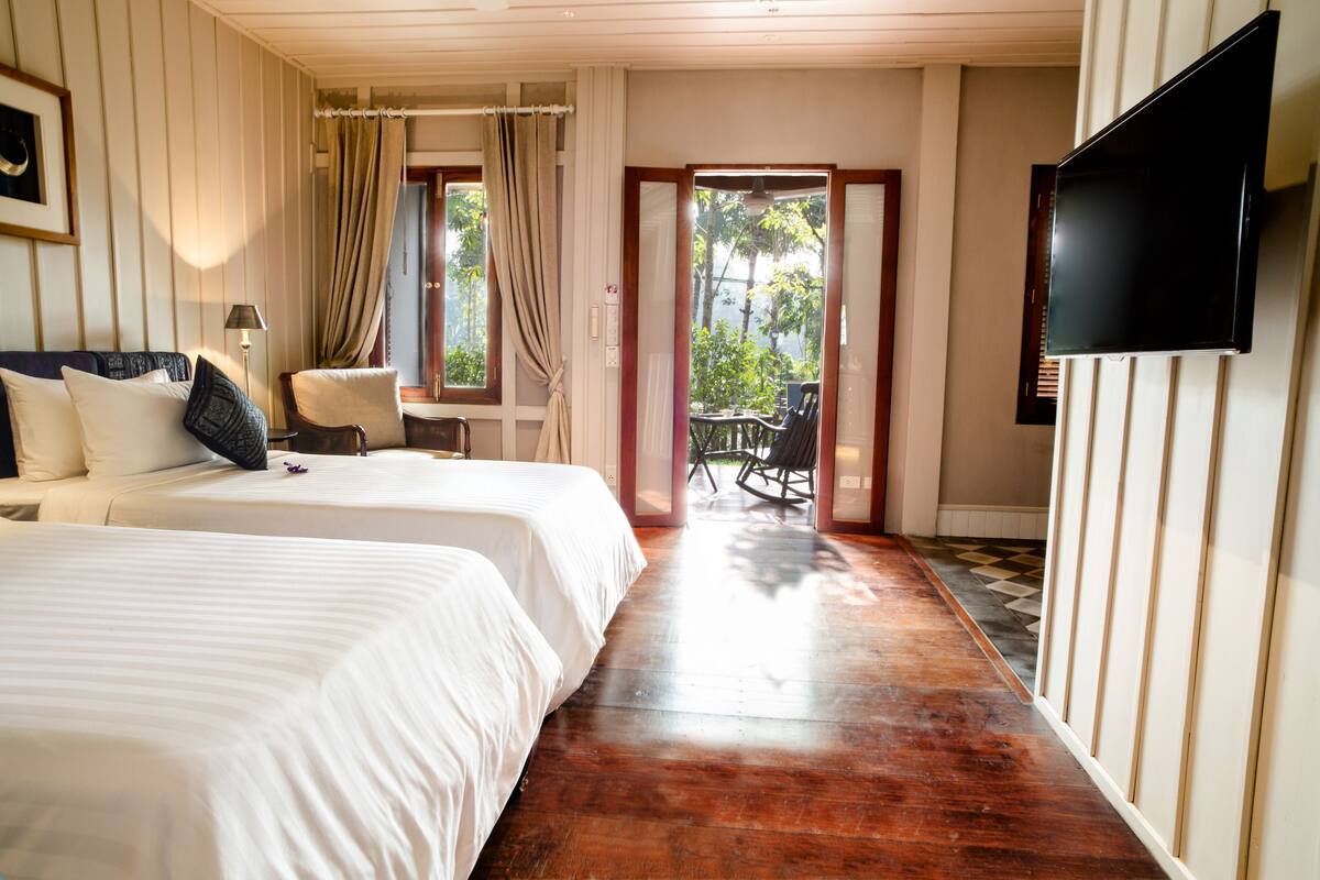 Habitación de hotel con dos camas, televisión y vistas al exterior.