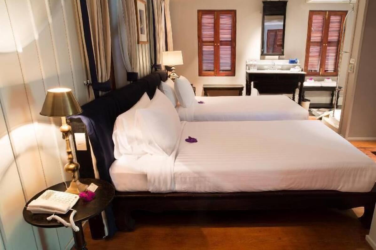 Habitación de hotel con una cama doble, una mesita de noche con lámpara, un escritorio con silla y un espejo.