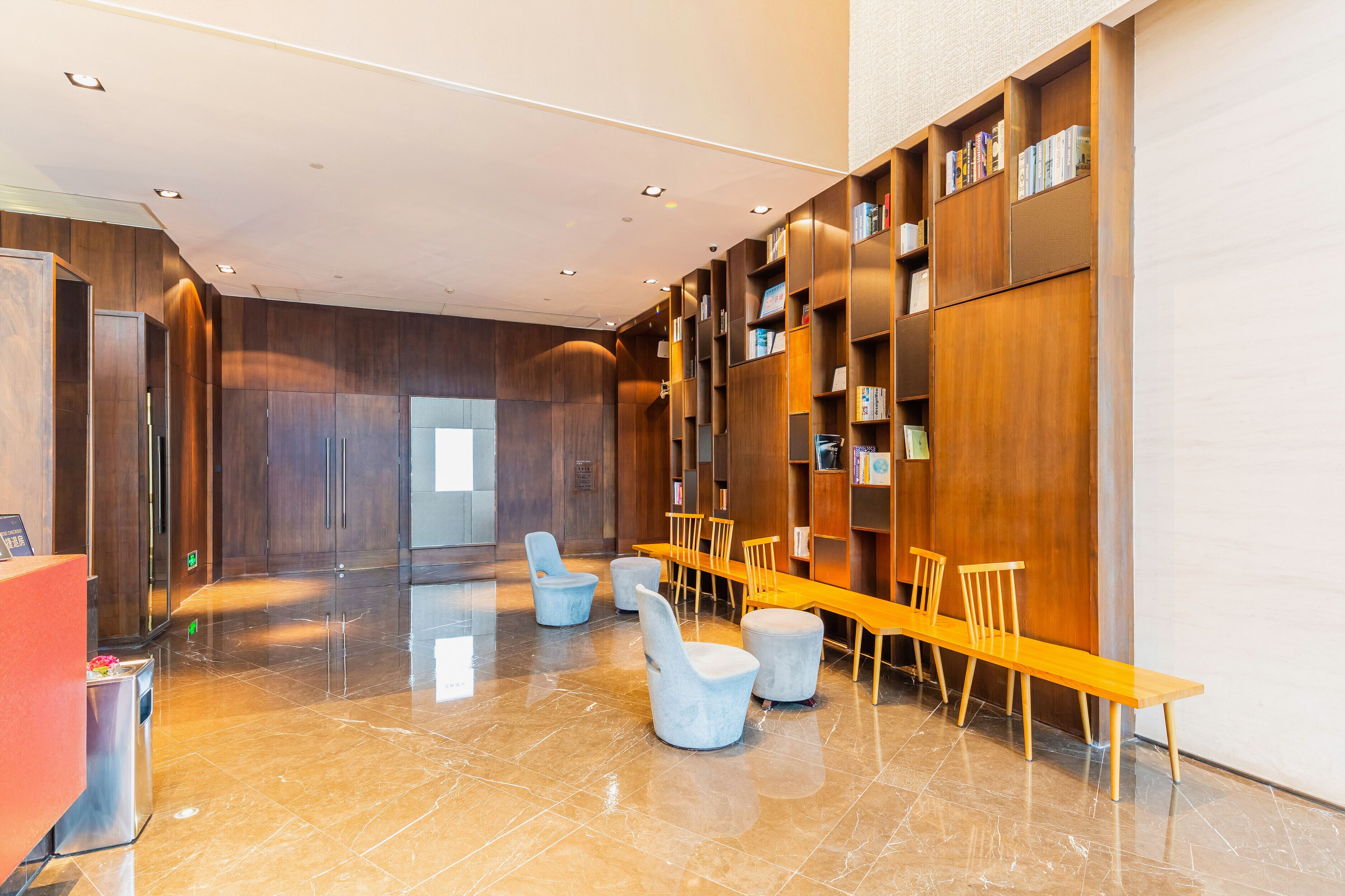 A modern lobby with a reception desk, seating area, and bookshelves.