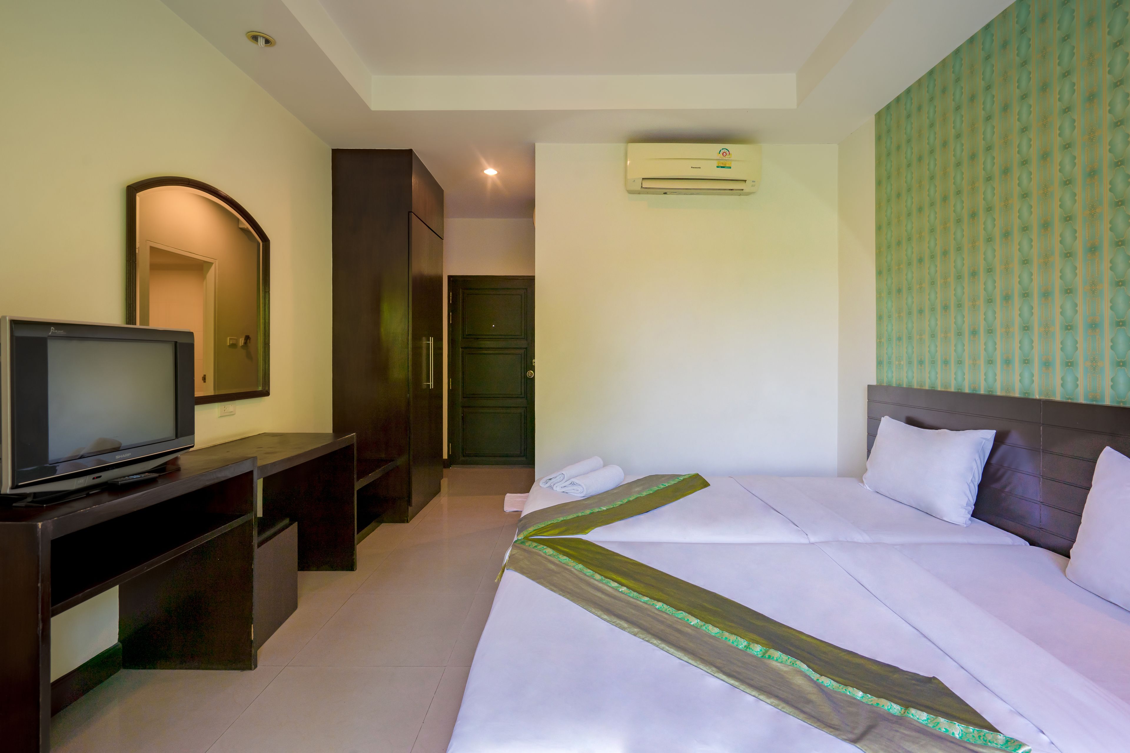 Une chambre d’hôtel équipée d’un lit, d’un téléviseur posé sur un meuble, d’une armoire et d’un appareil de climatisation.