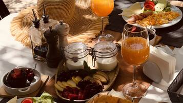 Une table dressée avec des aliments pour le petit-déjeuner, notamment des œufs brouillés, des toasts, des fruits et des boissons.