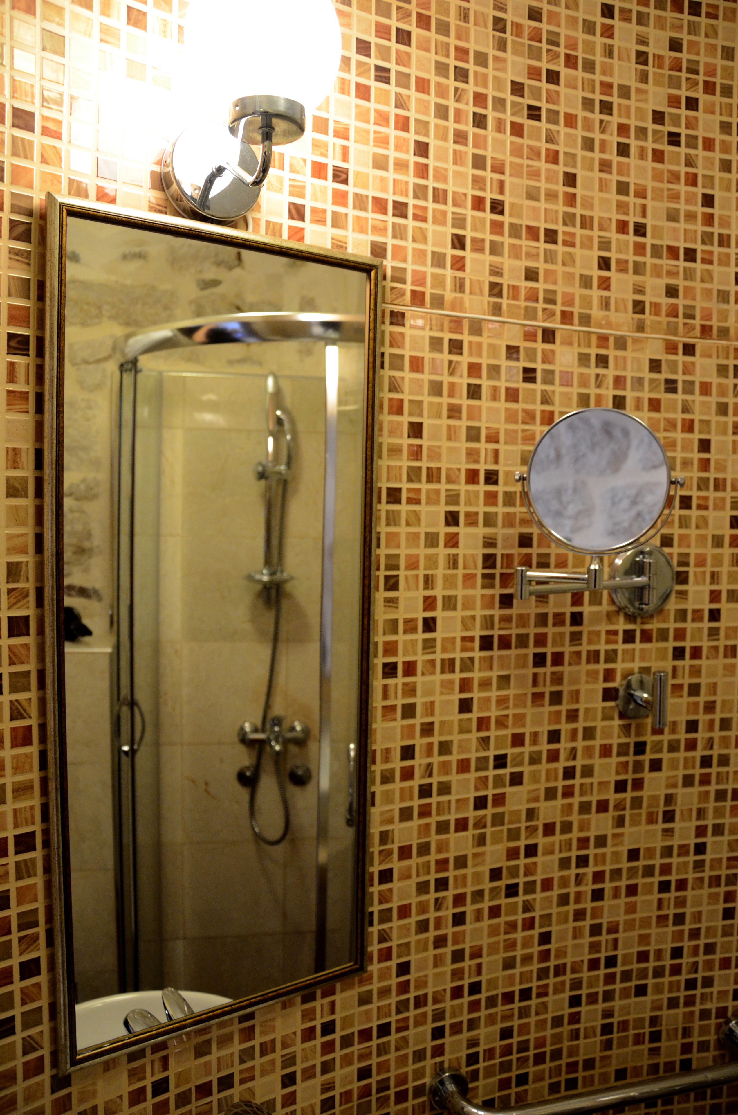 Un baño con ducha acristalada, espejo y pared de azulejos.