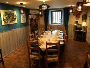 A dining room with a long table set for six, wooden chairs, and a vintage gramophone.