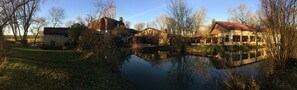 A serene lakeside setting with traditional buildings, a clear sky, and a calm water body reflecting the structures.