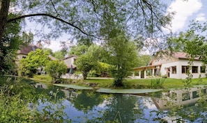 Una propiedad tranquila junto al lago, con un estanque rodeado de vegetación exuberante y casas tradicionales.