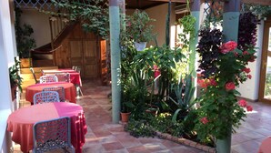 Un patio exterior con suelo de baldosas, manteles rojos y sillas de metal.