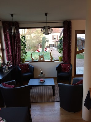 Sala de estar con vista a un jardín, que incluye un conjunto de sofás, una mesa de centro y una lámpara colgante.