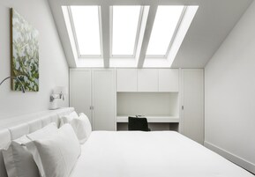 Una camera da letto moderna con un lucernario, un letto, una scrivania e un armadio.