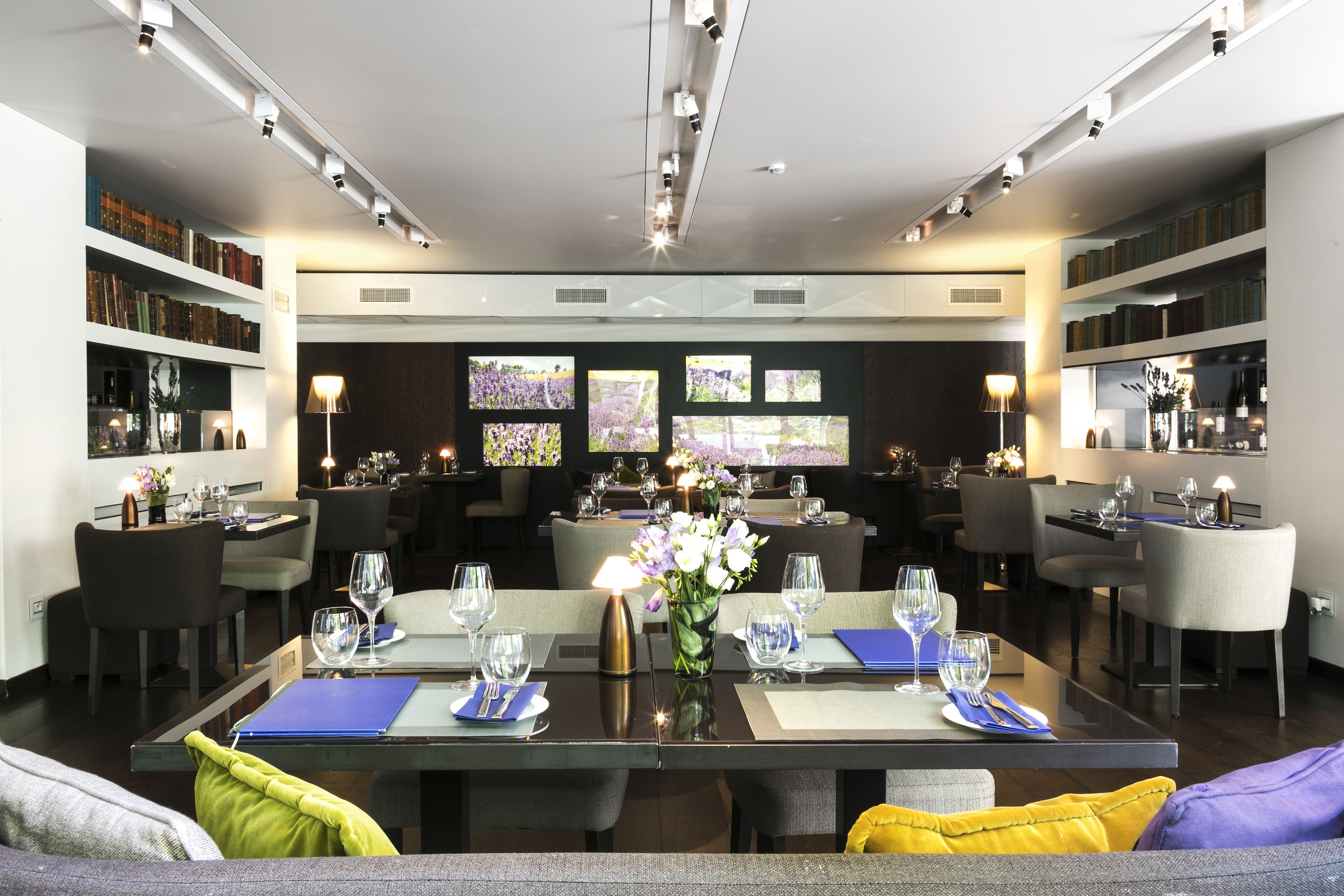 Un comedor moderno con varias mesas, sillas y un arreglo floral central.