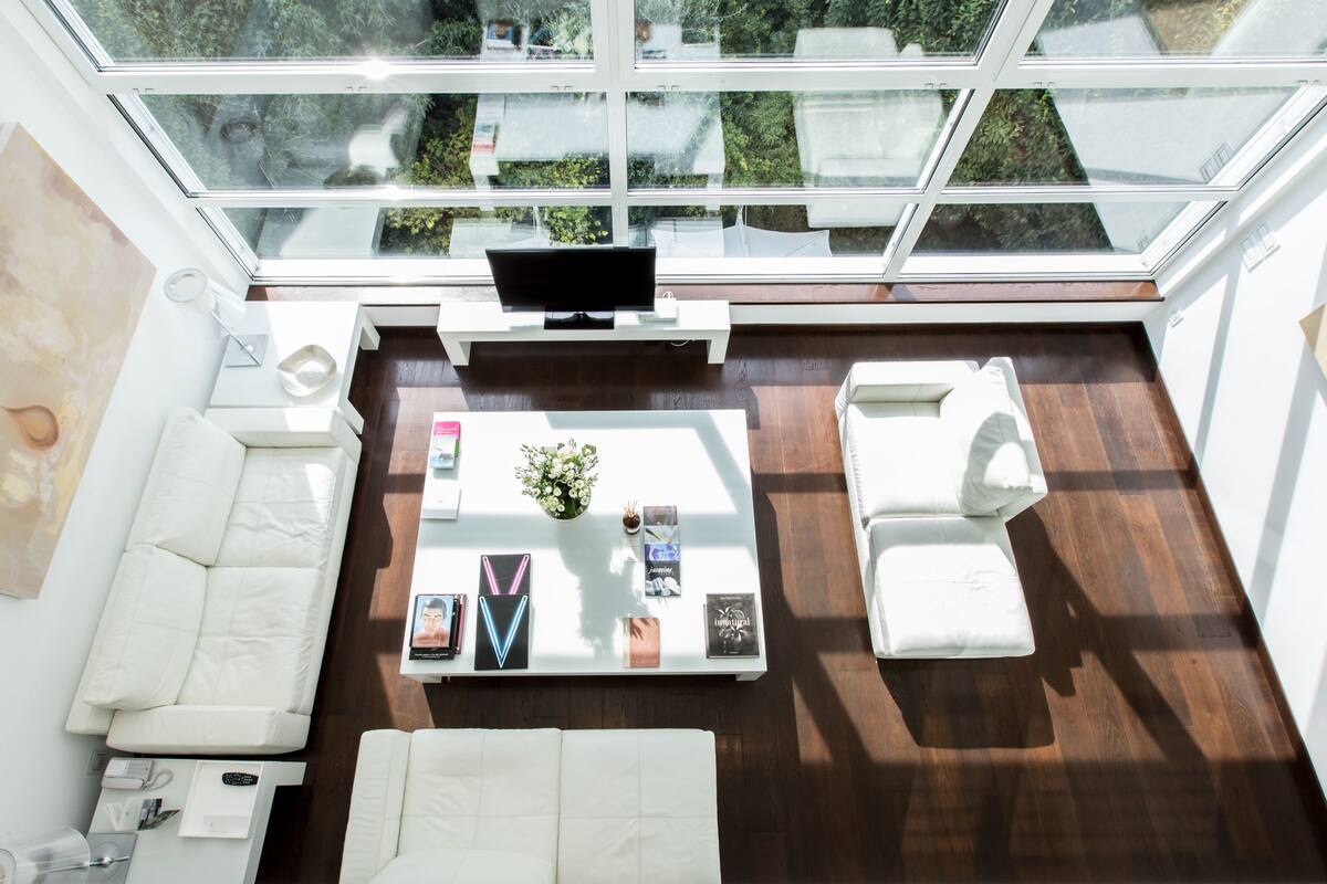 A modern living room with a white sofa, a white armchair, and a coffee table with books and a vase.
