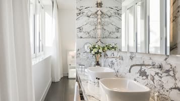 A modern bathroom with a large mirror, two sinks, and a marble backsplash.