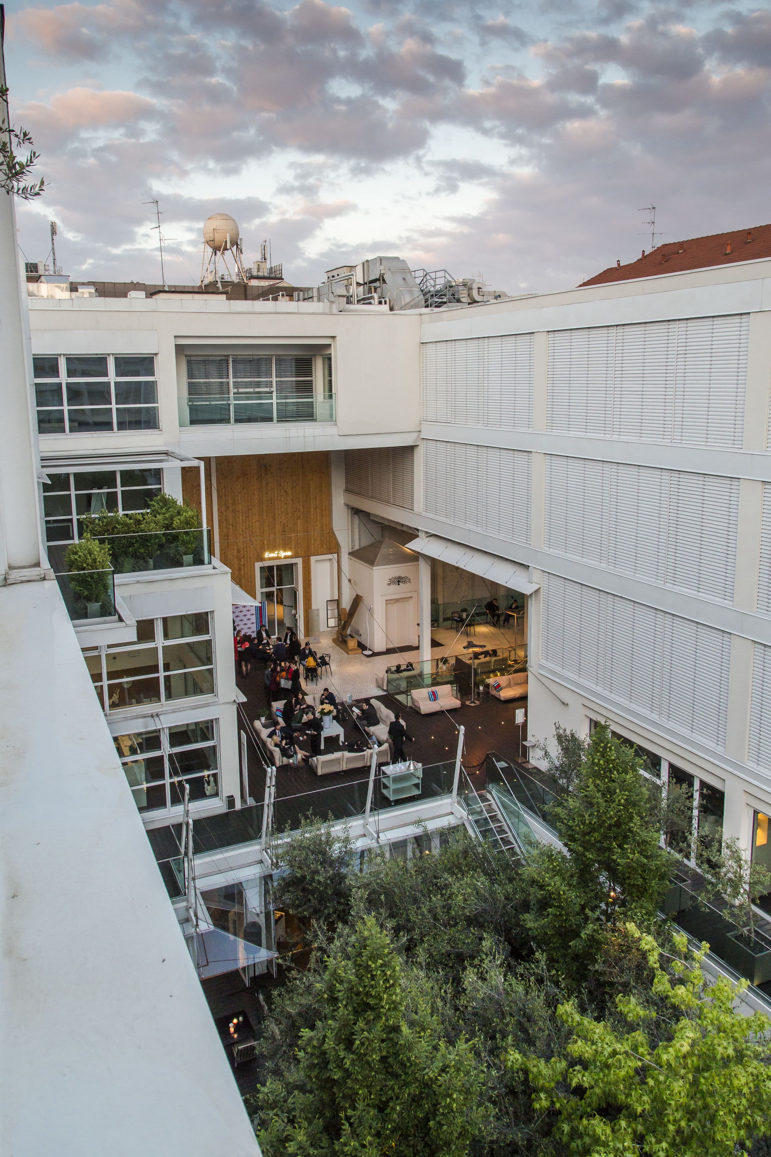 A multi-level building with a central atrium, glass railings, and outdoor seating areas.