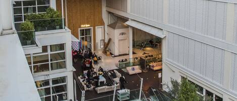 A multi-level building with a central atrium, glass railings, and outdoor seating areas.