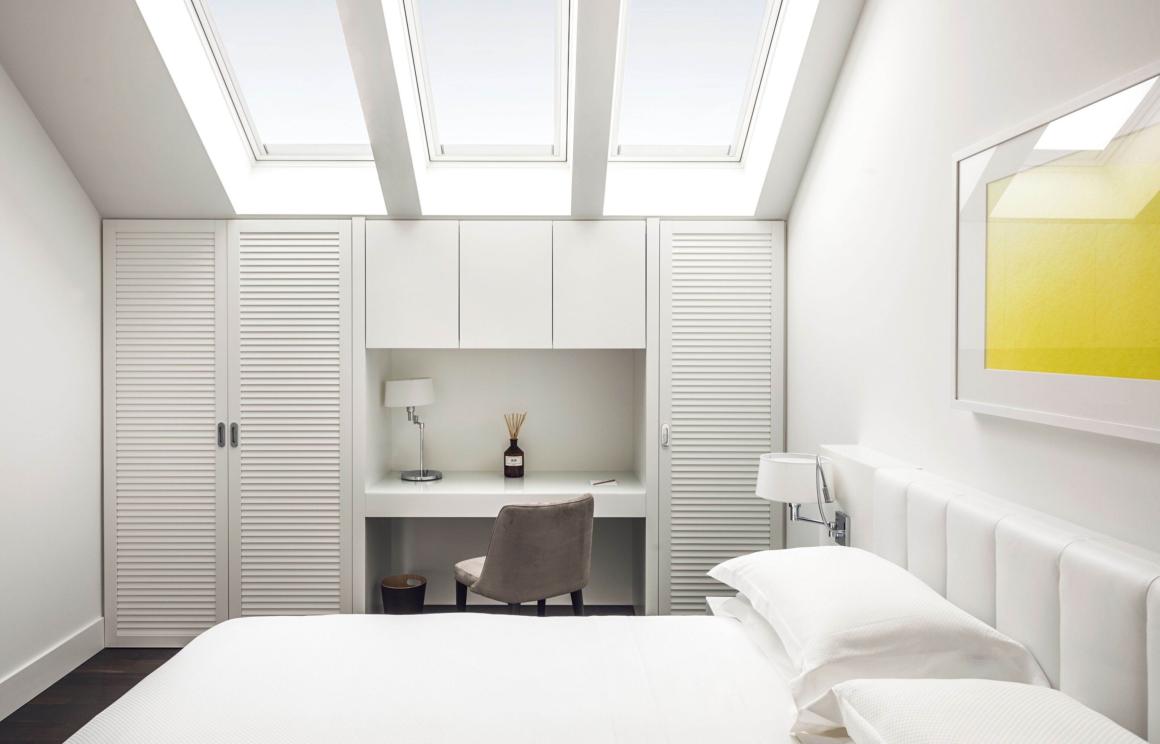 Une chambre moderne avec des fenêtres de toit, un lit, un bureau et une chaise.
